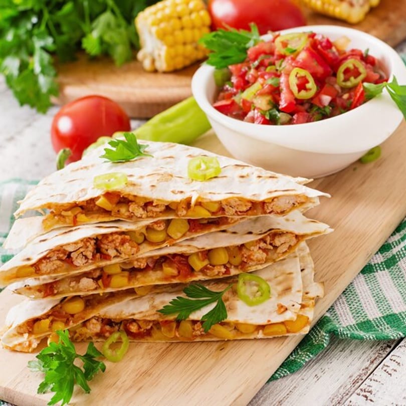 Stacked quesadillas with chicken and corn, served with fresh salsa, tomatoes, and corn on the cob.